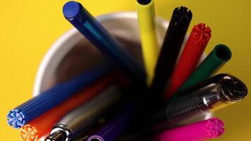 Different markers and pens in holder on yellow background video