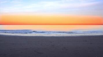 Ocean waves run on empty beach at bright orange sunset video