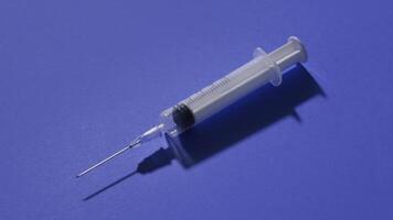 White syringe with long needle lies diagonally and fills video