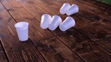 Small disposable white plastic cups moved by wind on table video