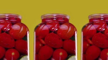 Green pickles and red tomatoes in large glass jars closeup video