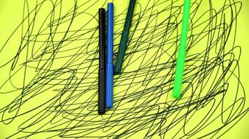 Markers fall down onto yellow paper with abstract pattern video