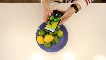Manicured woman hands hold smartphone making photos of fruit video