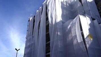 White cloth hangs on scaffolding against blue sky close up video
