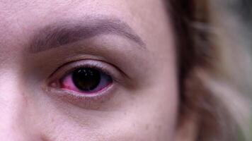 Young woman looks at camera while eye pupil changes color video