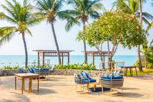 A beach with palm trees and a table with chairs photo