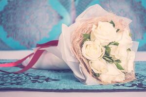 A bouquet of white roses on a bed photo