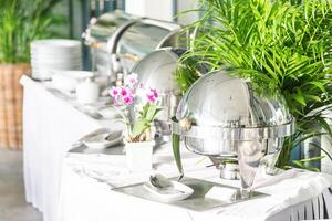 A buffet table with silver dishes and plants photo