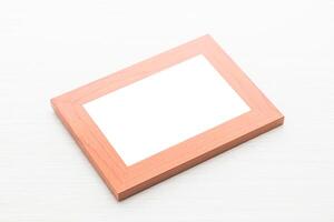 A blank white photo frame on a wooden surface
