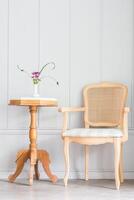 A chair and table in front of a white wall photo
