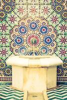 A colorful tile wall with a fountain in front of it photo