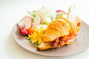 A croissant sandwich with a salad on a plate photo