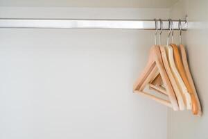 A closet with wooden hangers and clothes photo
