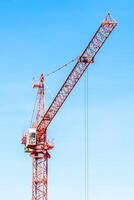 A large red crane is standing in front of a building photo