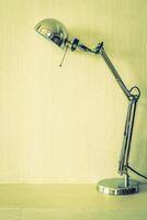 A lamp on a desk in front of a wall photo