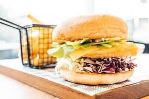 A large sandwich with coleslaw and fries on a wooden table photo