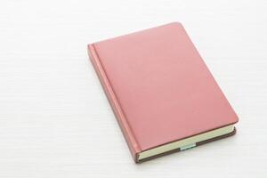 A pink notebook on a white table photo