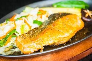 A piece of fish is on a plate with vegetables photo