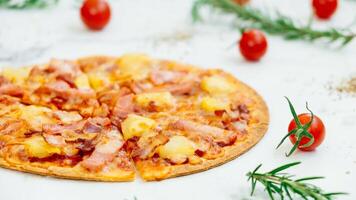 A pizza with ham and pineapple on a white table photo
