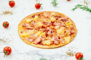 A pizza with ham, pineapple and tomatoes on a white background photo