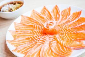 A plate of salmon on a table with a bowl of sauce photo