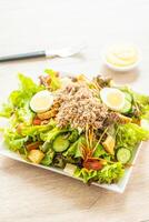 A plate of salad with a fork and knife on a table photo
