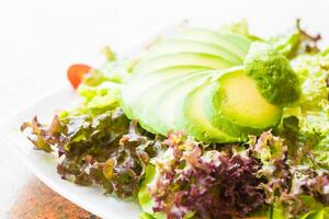 A plate of salad with avocado, tomatoes and lettuce photo