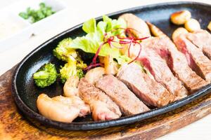 A steak is on a black plate with broccoli and other vegetables photo