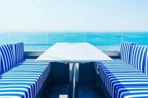 A table and chairs on a balcony overlooking the ocean photo