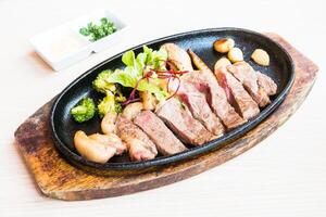 A steak on a black plate with broccoli and other vegetables photo