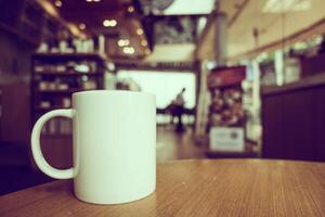 A white coffee cup sits on a table in a coffee shop photo
