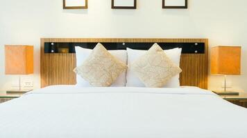 A white bed with two pillows and a lamp photo