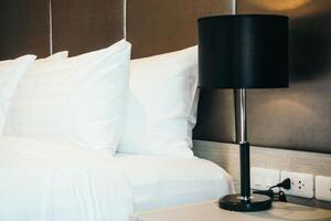A white bed with black pillows and a lamp photo