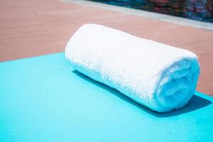 A white towel on a blue table near a pool photo