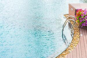 A wooden deck with a pool and a flower pot photo