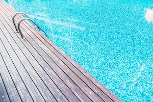 A wooden deck with a swimming pool and a ladder photo