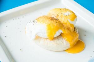 Eggs benedict with orange sauce on a white plate photo