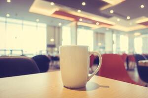 Coffee cup on table in restaurant with bright lights photo