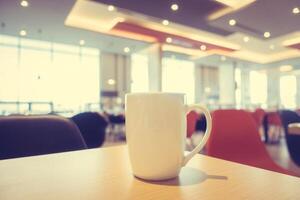 Coffee cup on table in restaurant with bright lights photo