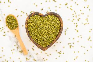 Green peas in heart shape on white background photo