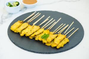 Thai satay chicken skewers on a black slate photo