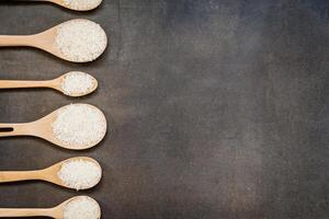 Six wooden spoons with rice in them on a black background photo