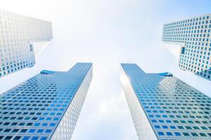 Two tall buildings with windows and sky in the background photo