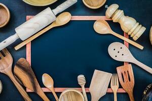 Various wooden utensils and spoons arranged around a blackboard photo