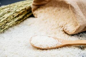 White rice in a sack and a wooden spoon on a black background photo