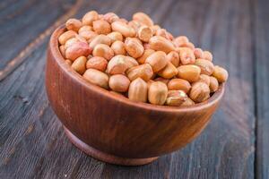 Peanuts in a wooden bowl on a wooden table photo