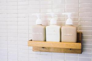 A wooden shelf holding three bottles of soap photo