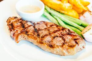 A plate of food with a steak, green beans and a side dish photo