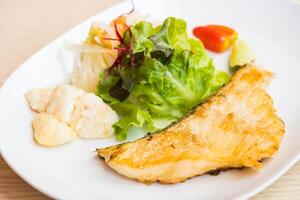 A plate with a fish and salad on it photo