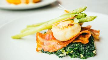 A plate with asparagus, bacon and scallops photo